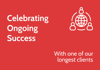 Red background with white text reading "celebrating ongoing success with one of our longest clients" and a graphic of people around a globe.
