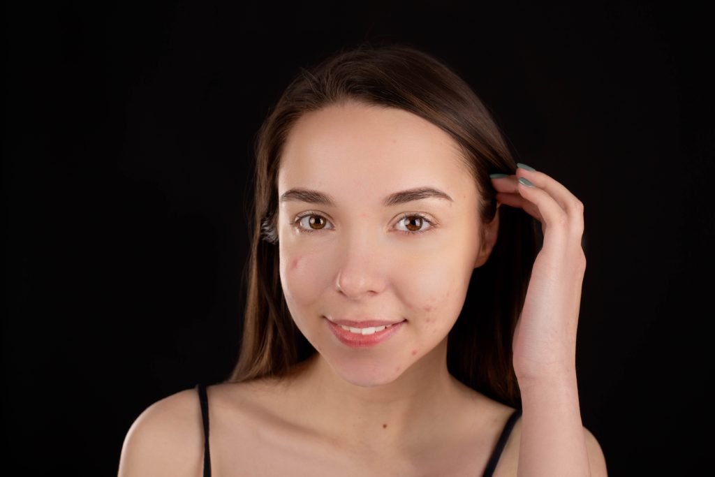 Photo of person touching hair in front of a black wall