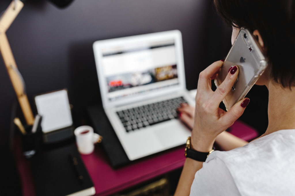 Person sitting at a desk with an open laptop, talking on the phone