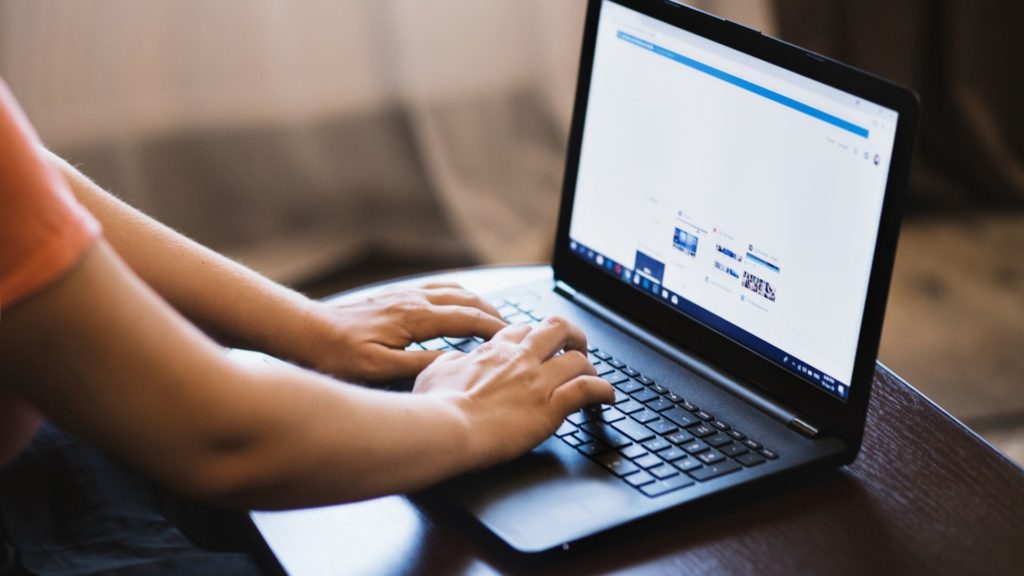 Hands typing on a laptop on a desk