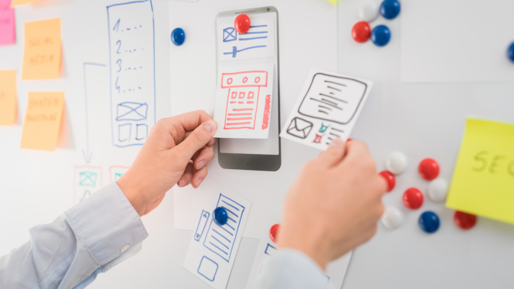hands laying out potential website drafts on a whiteboard to increase digital accessibility