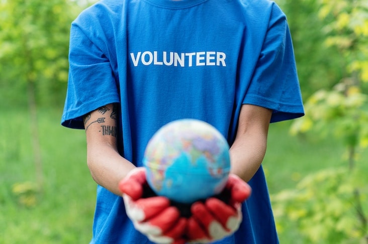 Person wearing blue "volunteer" shirt holding up a small globe