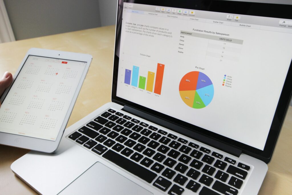 Image by Pixabay from Pixels showing a laptop with pie charts and regular chart, with a tablet in a left hand showing a calendar.