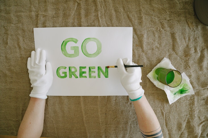 Hands from above painting "go green" on a piece of paper
