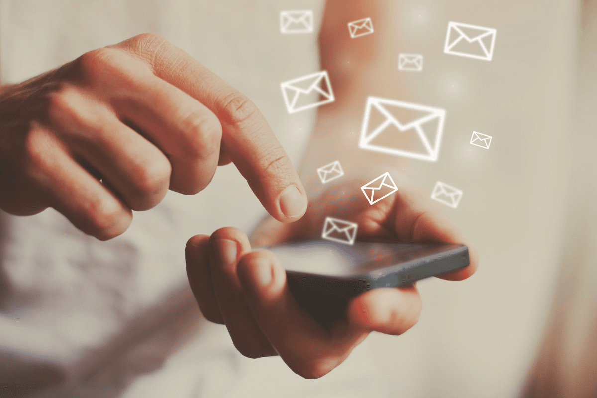 Image of a hand holding a phone and emails floating out of the phone for email marketing.