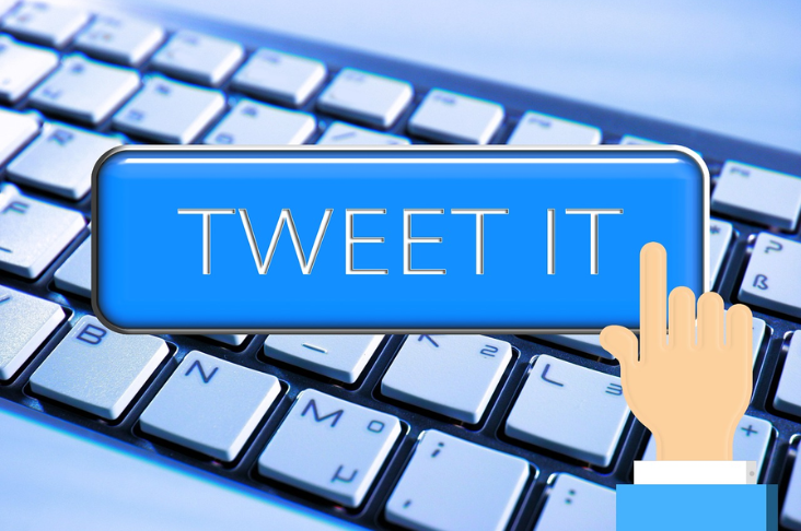 Keyboard with a text box reading "tweet it" and a finger pressing it.