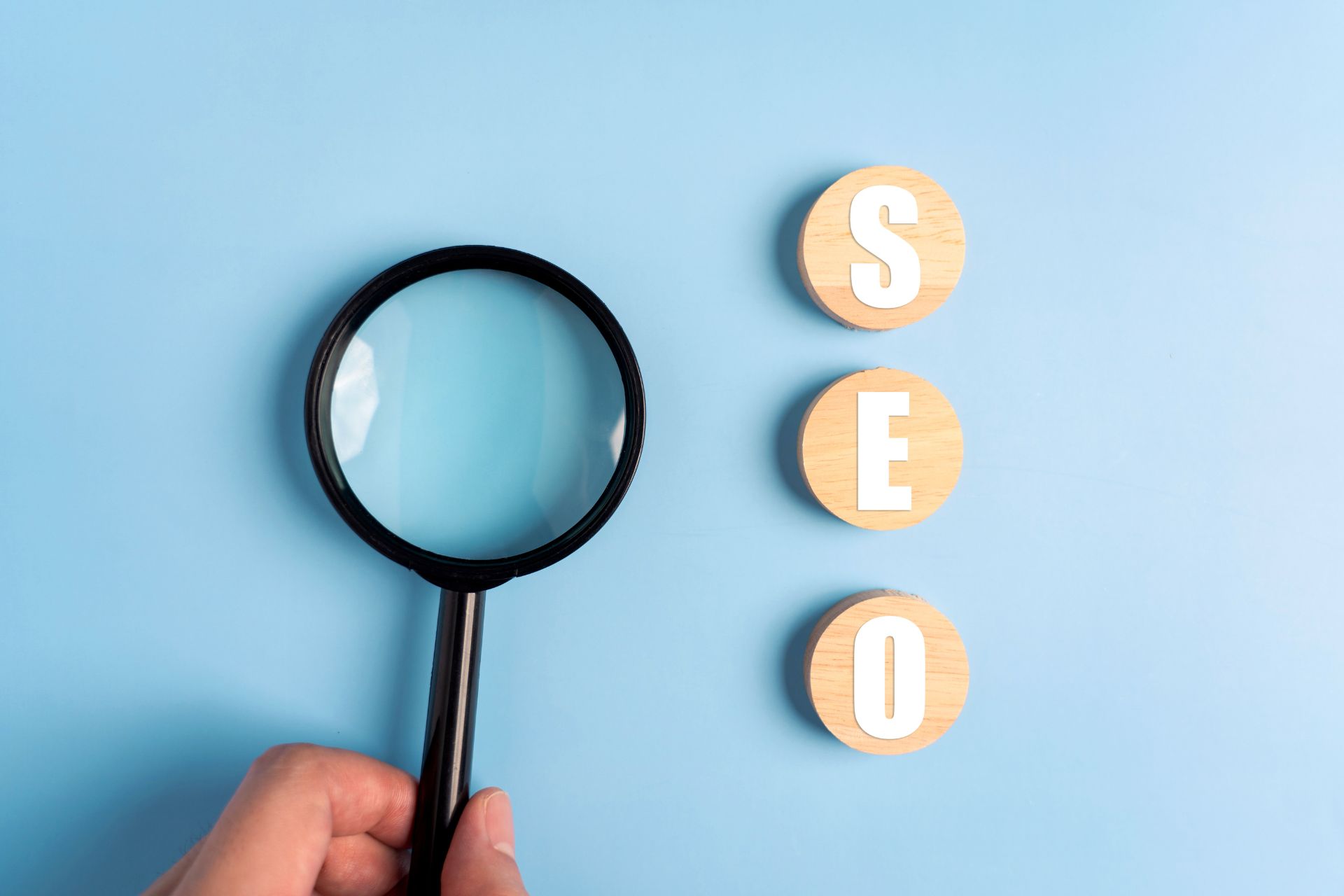 Magnifying glass over blue background beside tiles that spell SEO